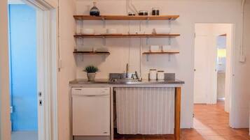 A compact kitchen with built-in shelves, a dishwasher, and a small countertop.