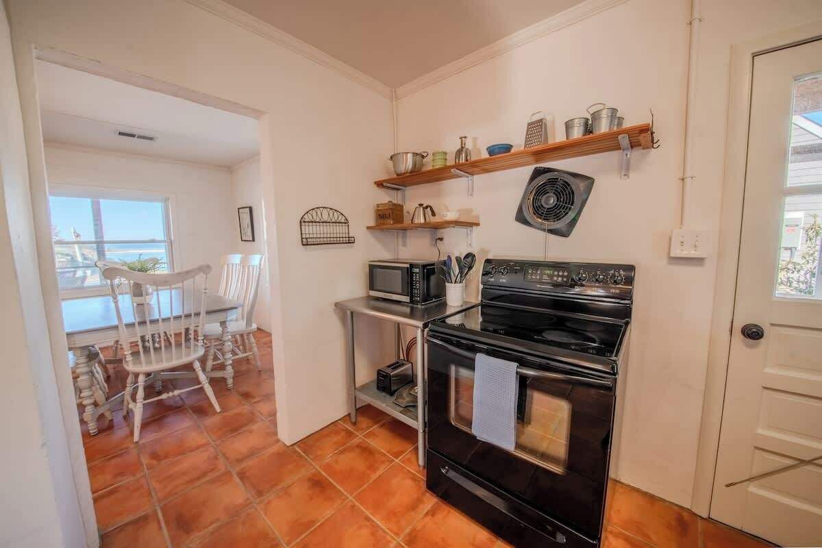 Una cocina compacta con estufa, microondas y repisas superiores.
