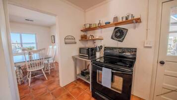 Una cocina compacta con estufa, microondas y repisas superiores.