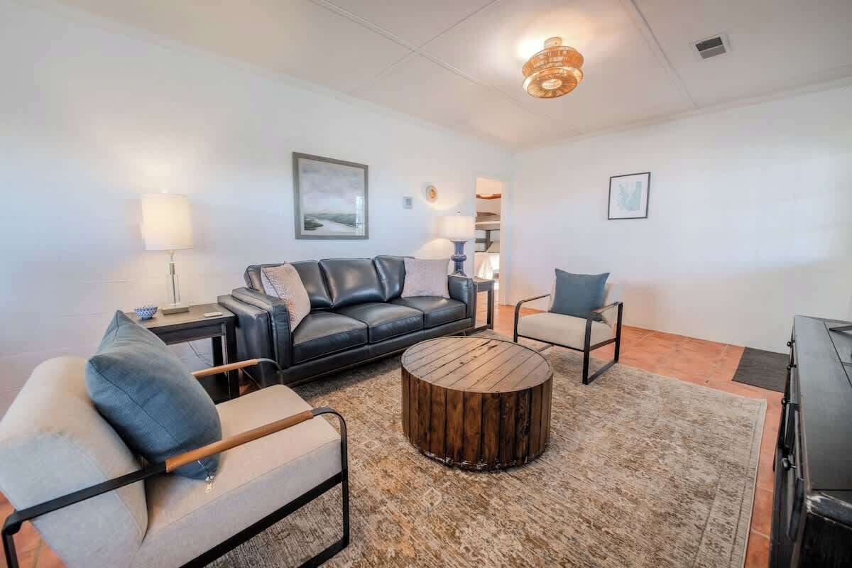 Ein modernes Wohnzimmer mit einem Ledersofa, einem runden Couchtisch und einem Sessel.