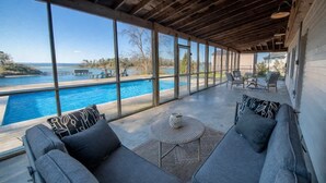A covered outdoor seating area with a view of a pool and lake. - The Bungalow, Pool, Dock, Kayaks, & Game Room (Topping)