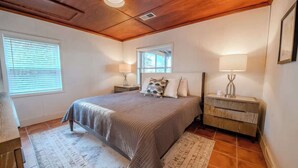 A bedroom with a bed, bedside tables, a window, and a nightstand. - The Bungalow, Pool, Dock, Kayaks, & Game Room (Topping)