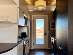 Una cocina moderna con horno empotrado, microondas y cafetera.