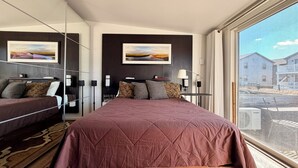 A modern hotel room with a large bed, a bedside table, a lamp, and a view of the outside. - New Listing. A short walk to the beach. (Provincetown)
