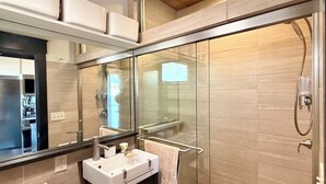 A modern bathroom with a glass shower enclosure, a white sink with a mirror above it, and a dark wooden vanity. - New Listing. A short walk to the beach. (Provincetown)