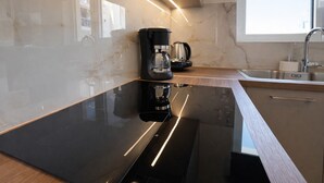 Una cocina moderna con encimera negra, cafetera y fregadero.