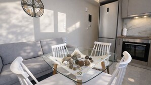 Una cocina moderna con una mesa de comedor de vidrio, sillas blancas y un sofá gris.
