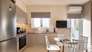 Una cocina moderna con refrigerador, estufa, pileta y comedor con sillas y mesa.