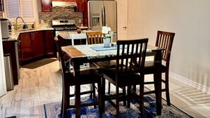 Een moderne keuken met houten kastjes, een roestvrijstalen koelkast en een eethoek met een tafel en stoelen.