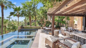 Ein Poolbereich mit Liegestühlen, einer Pergola und Palmen.