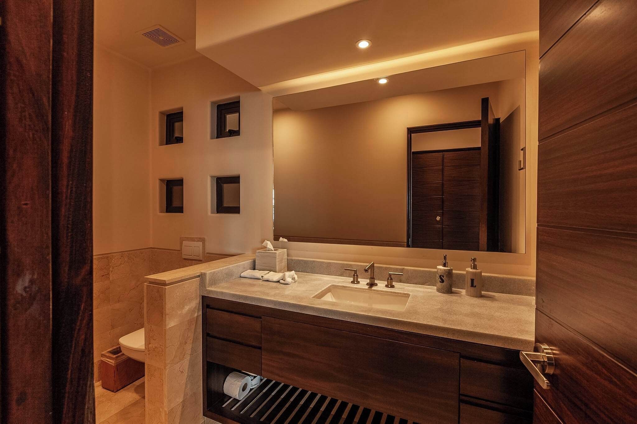 Un baño moderno con un espejo grande, dos lavamanos y un inodoro.