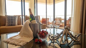Ein Zimmer mit Glastisch, einer Moët-Champagnerflasche, einem Glas und Erdbeeren.