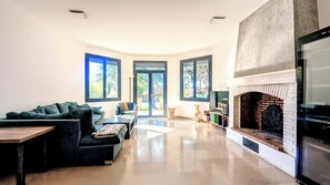 Un salon moderne avec une cheminée, de grandes fenêtres et un canapé.