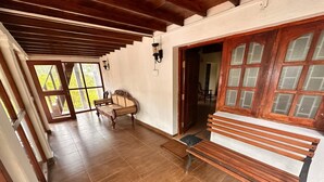 Una habitación amplia con un banco de madera, un sofá y una puerta que da a otra zona.