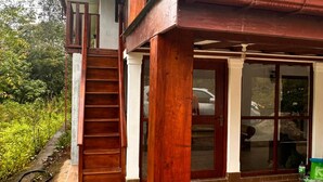 Una estructura de madera con un porche cubierto, una escalera y una puerta de vidrio.