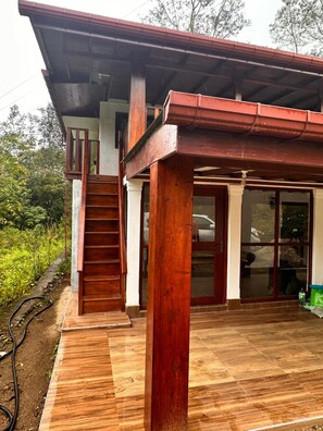 A wooden structure with a covered porch, a staircase, and a glass door.