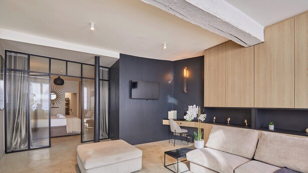 A modern living room with a sofa, a coffee table, and a TV mounted on the wall. - Superb Duplex in the Center of Paris (Paris)