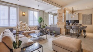 A modern living room with a sofa, coffee table, and a dining area with chairs. - Superb Duplex in the Center of Paris (Paris)