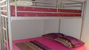 Una litera con colchón rosa, dos almohadas y una manta.
