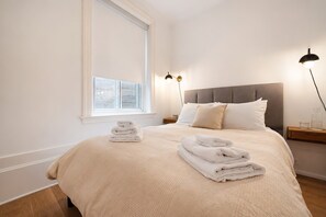 A bedroom with a large bed, two bedside tables, a window, and a nightstand with a lamp. - 3 Bedroom Apt in Downtown Montreal (Montreal)
