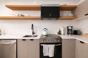Eine moderne Küche mit Einbauofen, Wasserkocher, Kaffeemaschine und Geschirrspüler.