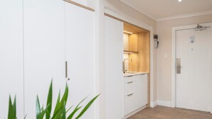 Eine moderne Küche mit weißen Schränken, einer Holz Arbeitsplatte und einer Tür mit Lichtschalter.