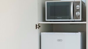 Ein weißes Schranksystem mit einer Mikrowelle obenauf und einem Kühlschrank darunter.