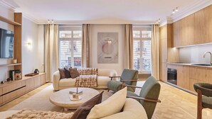 A modern living room with a sofa, armchairs, a coffee table, and a TV. - Luxurious Airconditioned Apartment Arc de Triomphe (Paris)