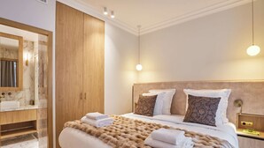 A modern bedroom with a large bed, wooden wardrobe, marble bathroom, and pendant lighting. - Luxurious Airconditioned Apartment Arc de Triomphe (Paris)