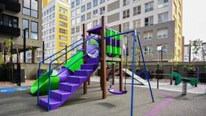 A playground with a purple slide, green and purple climbing area, and swings. - Studio em frente a UFSC e HU - 309A (Florianópolis)