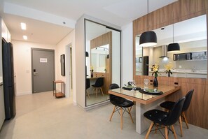 Una cocina moderna con zona de comedor, armarios de madera y un separador de vidrio.