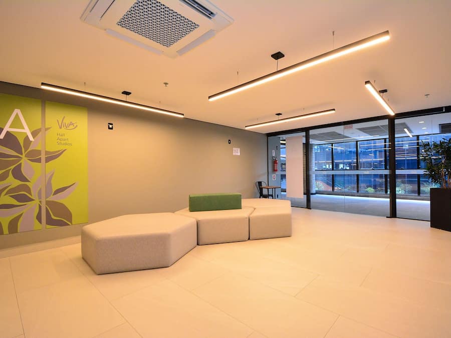 Uma área de recepção moderna com disposição de assentos, uma janela ampla e um painel decorado com motivos florais.
