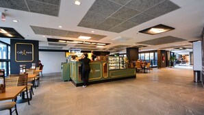 En rummelig café med skranke, siddepladser og udsigt ud.