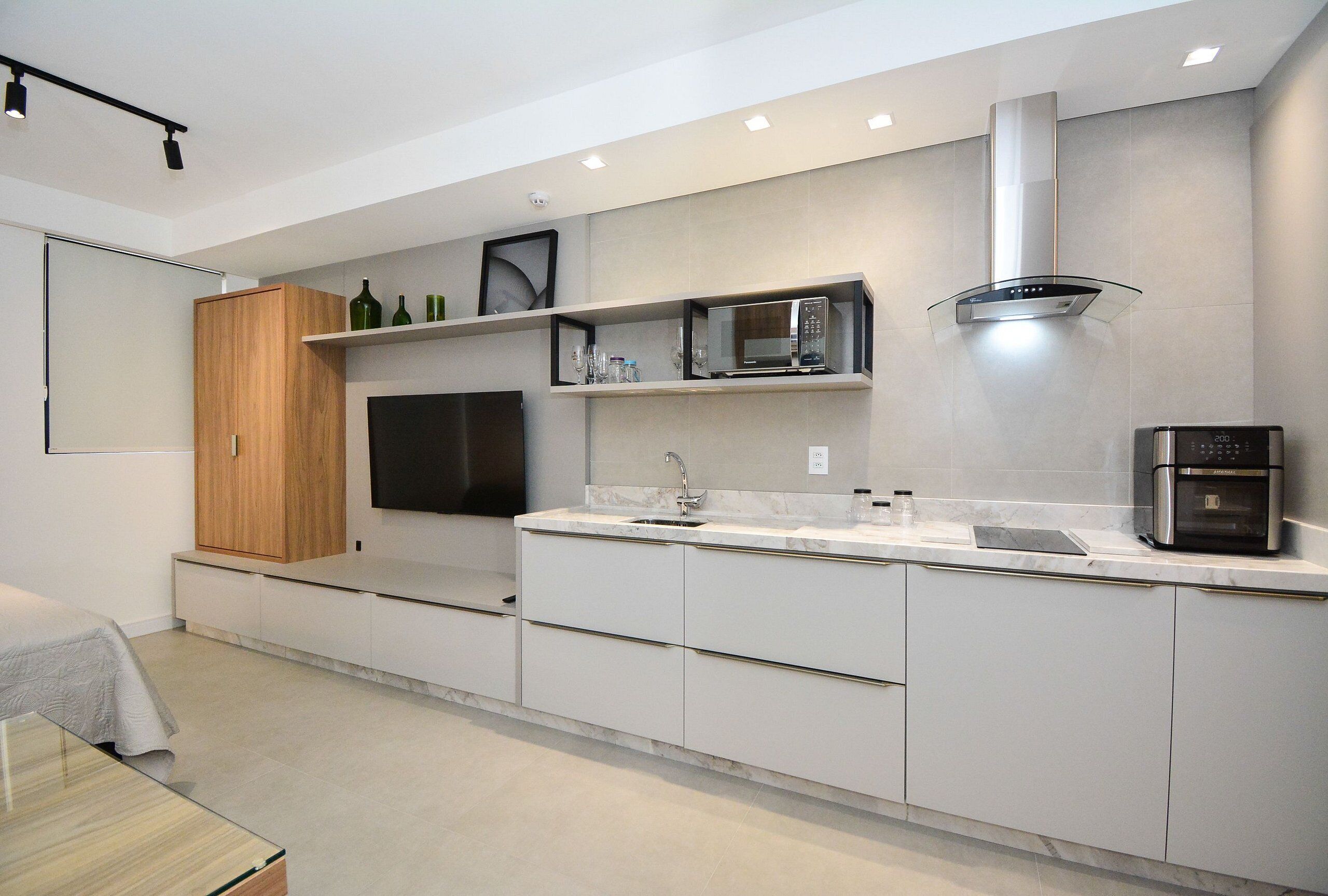 A modern kitchen with built-in appliances, a flat-screen TV, and a minimalist design.