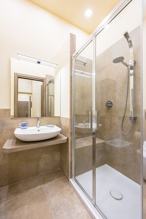 Une salle de bain moderne avec une douche à parois de verre, un lavabo blanc et un miroir au-dessus.