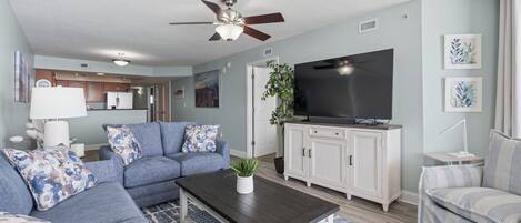 A living room with a sofa, coffee table, TV, and cabinets.