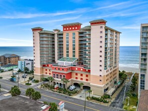 Ein mehrstöckiges Hotel mit Innenhof, Blick auf den Strand und einem Parkplatz.