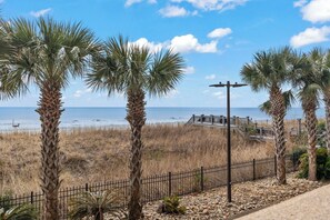 Blick auf die Küste mit Palmen, einem Strand und einer Fußgängerbrücke.
