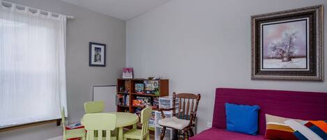 Una sala de estar con un sofá, sillas, una estantería y un cuadro en la pared.
