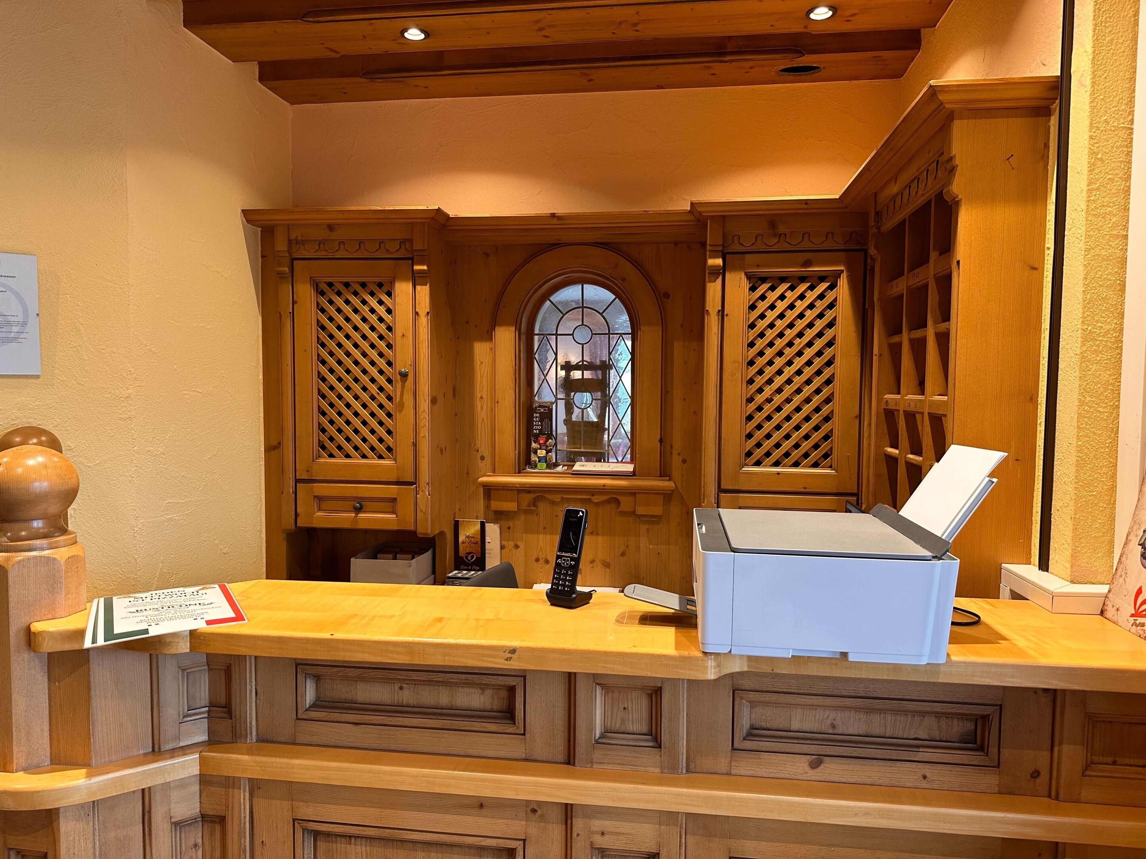 A reception desk with a wooden design, a telephone, and a computer.