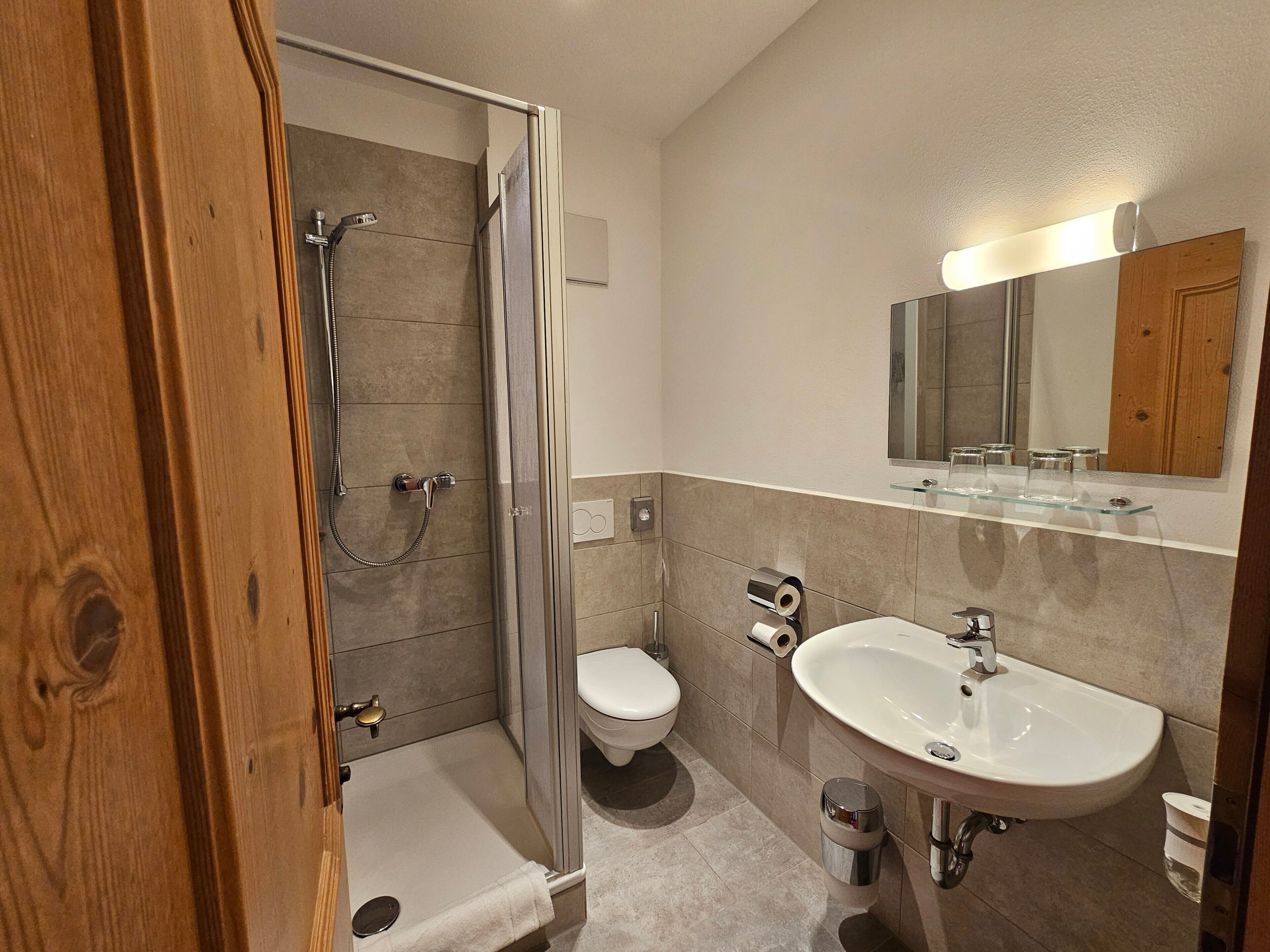 Une salle de bain moderne avec une douche à parois de verre, des toilettes, un lavabo et un miroir.