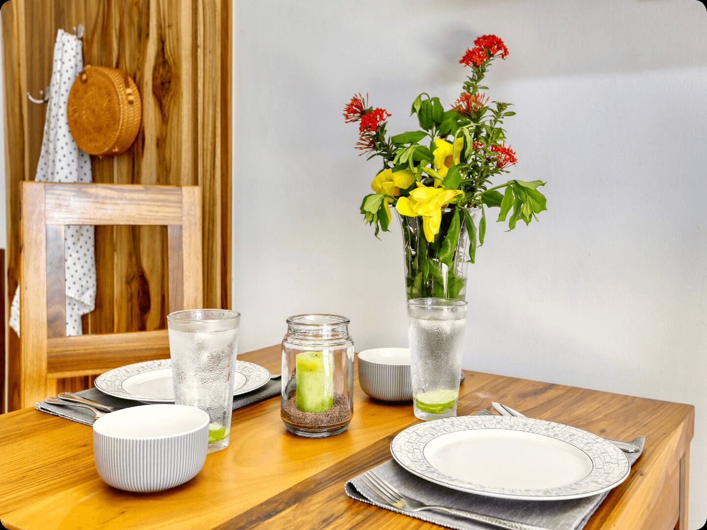 A dining table with a vase of flowers, glasses, and plates.