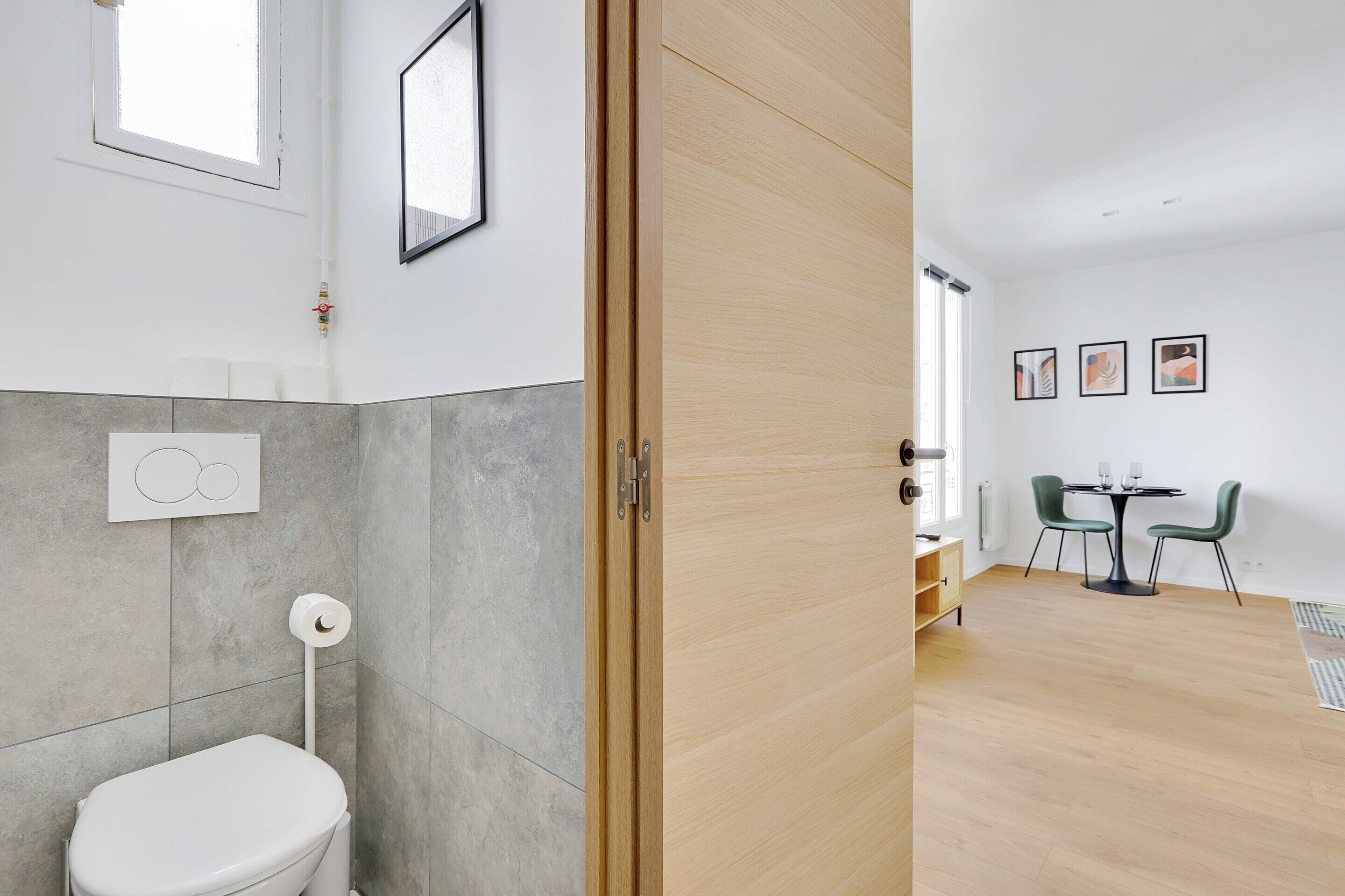 A modern bathroom with a toilet, a towel rack, and a shower area.