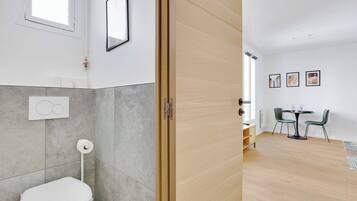 A modern bathroom with a toilet, a towel rack, and a shower area.