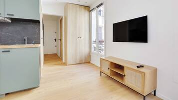 Een moderne keuken met een marmeren spatwand, een houten kast en een aan de muur bevestigde televisie.