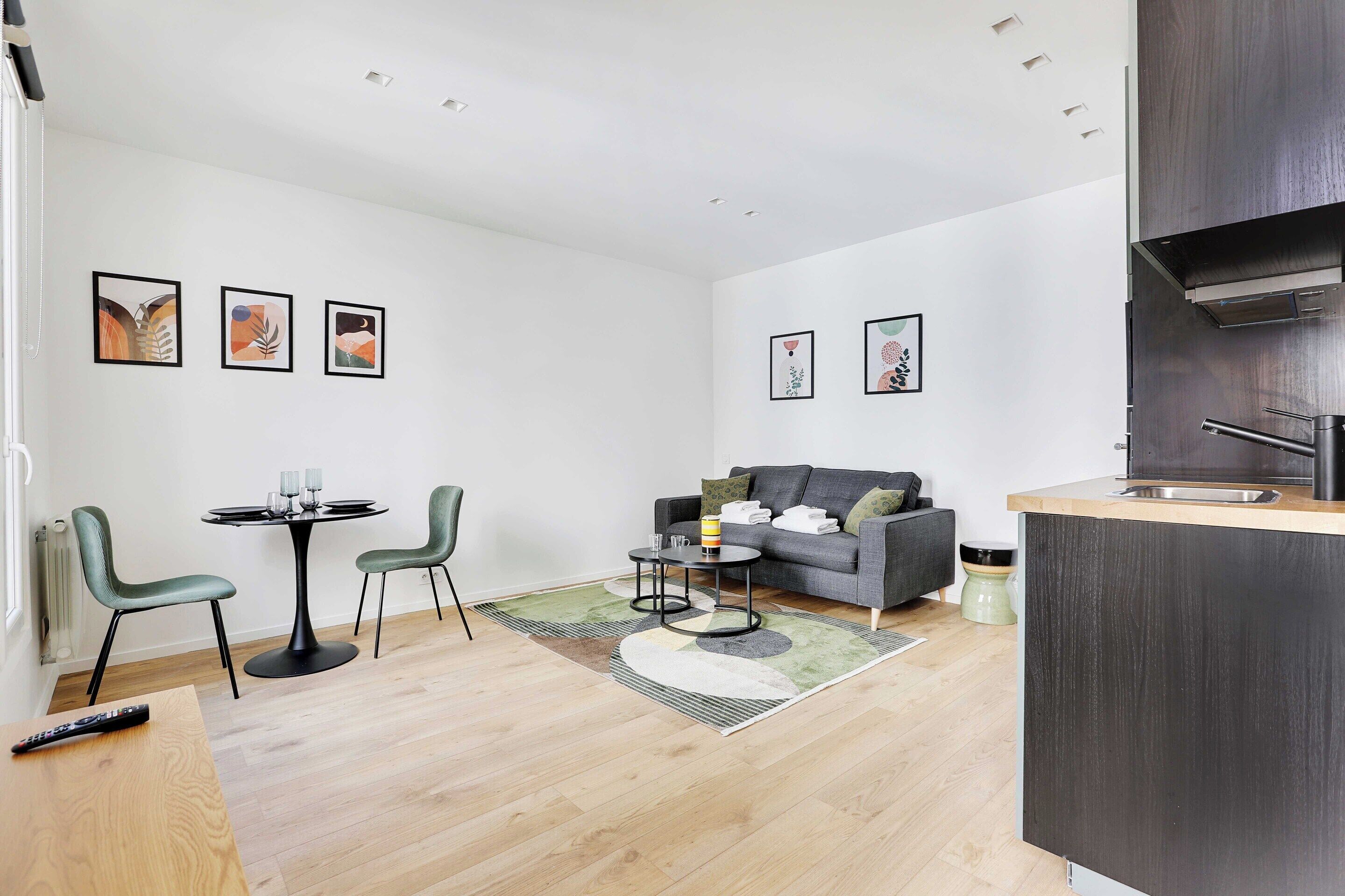 Een moderne woonkamer met een bank, een eettafel met stoelen en kunstwerken aan de wanden.