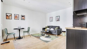 A modern living room with a sofa, a dining table with chairs, and artwork on the walls. - Charming Studio for 2P - Near Parc Monceau (Paris)