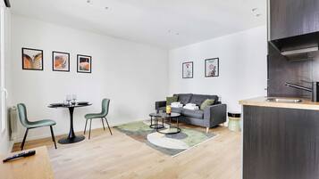 Een moderne woonkamer met een bank, een eettafel met stoelen en kunstwerken aan de wanden.