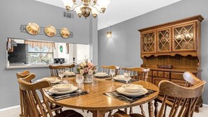 A dining room with a round wooden table set for six, surrounded by wooden chairs. - Upstay Golfer's Retreat w Patio at Ventura Resort (Orlando)