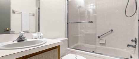 Uma casa de banho moderna com cabine de duche em vidro, lavatório com espelho e sanita.
